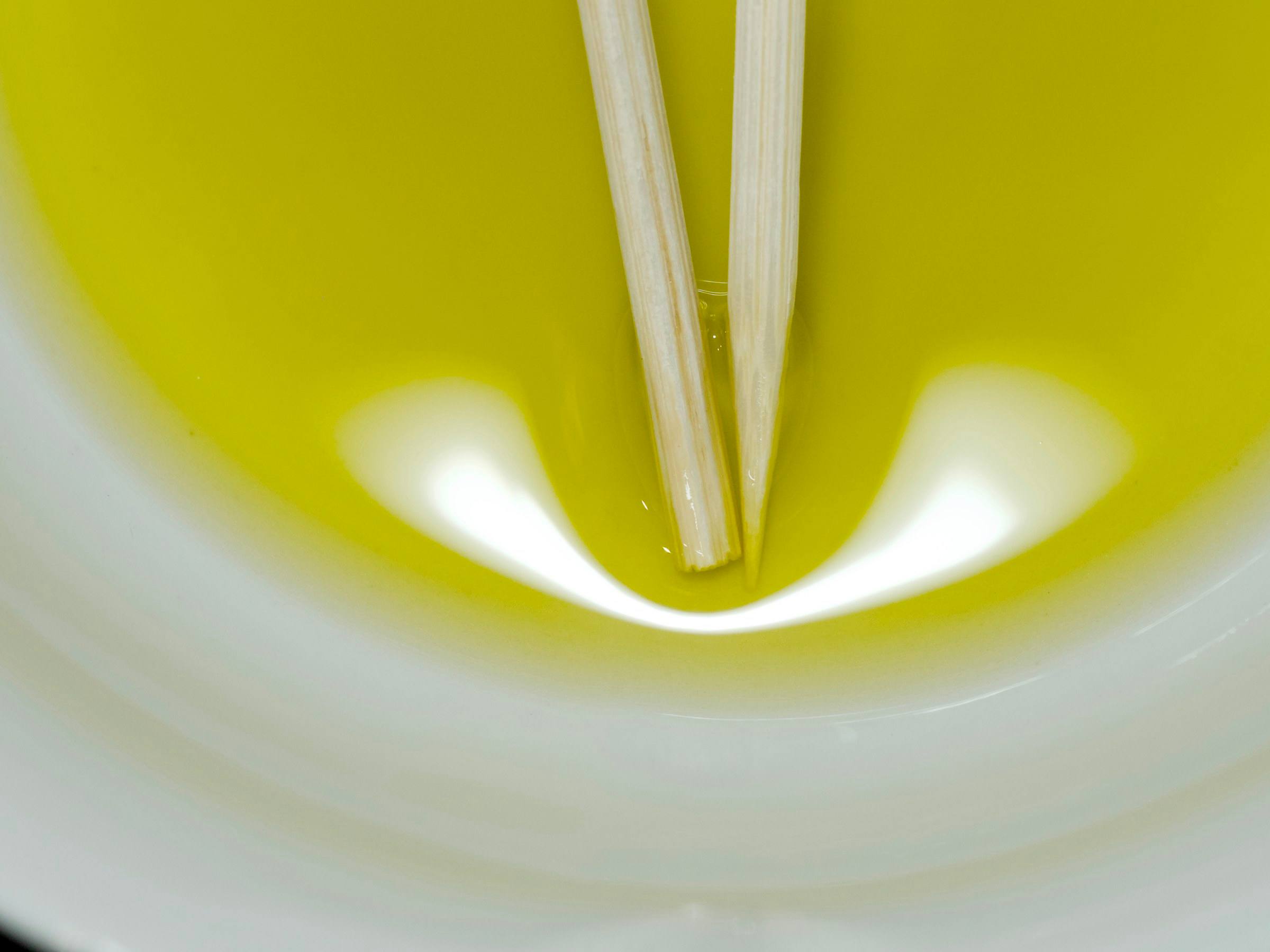 Assaggio dell'olio nuovo, giallo-verde, in una ciotola bianca